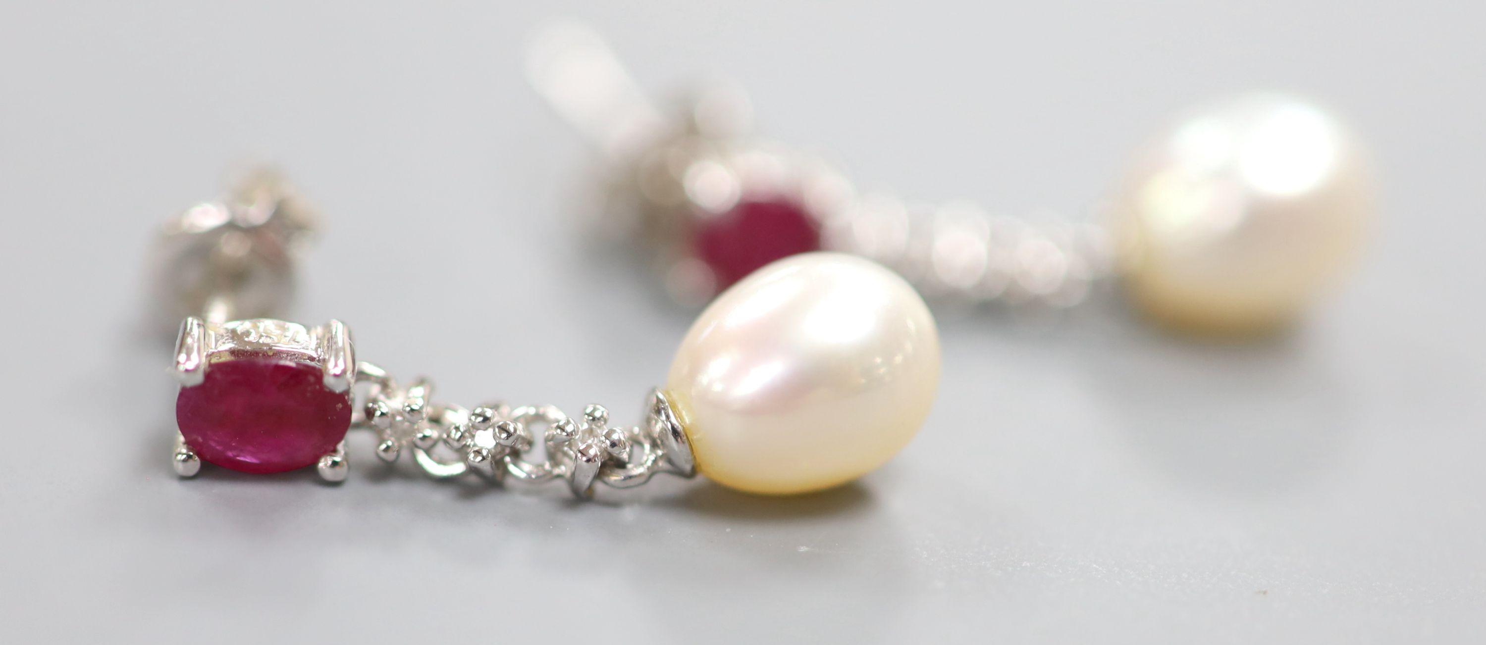 A modern pair of 750 white metal, ruby, diamond chip and cultured pearl set drop earrings, 22mm, gross 2.9 grams.